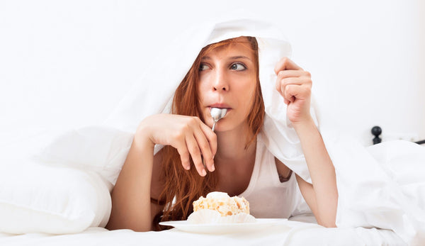 Woman enjoying dessert under white blanket.