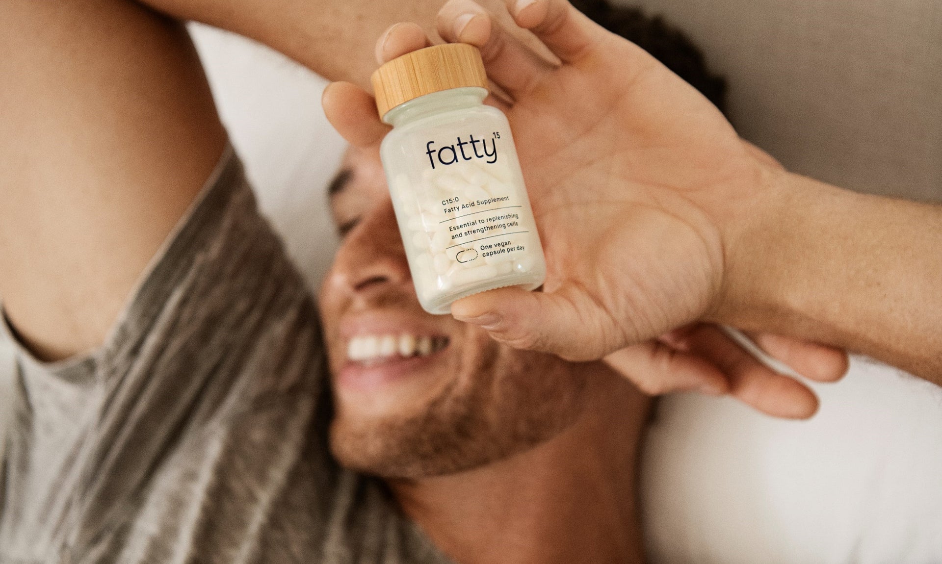 Smiling person holding a bottle of Fatty15's C15 supplement.