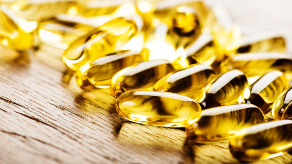 Golden oil capsules on wooden surface.