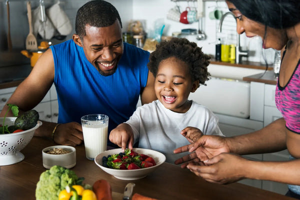 Family enjoying healthy breakfast with fruits and milk in kitchen.