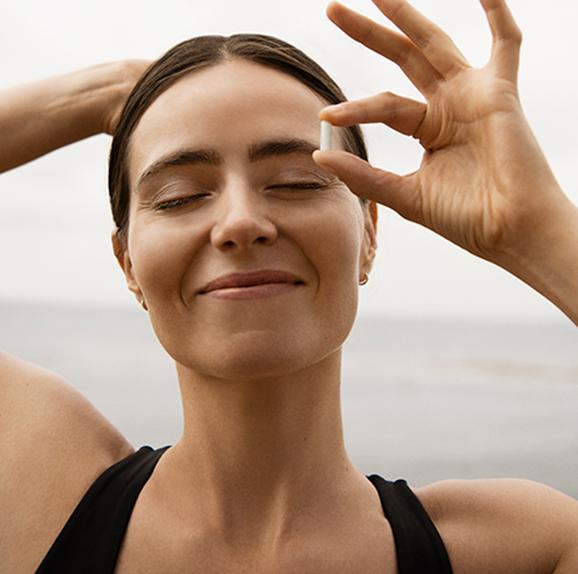 
                Woman smiling with a sense of well-being near the ocean.