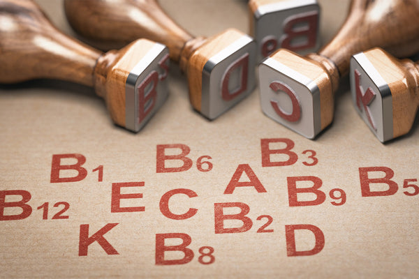Rubber stamps with red vitamin letters on brown paper background.
