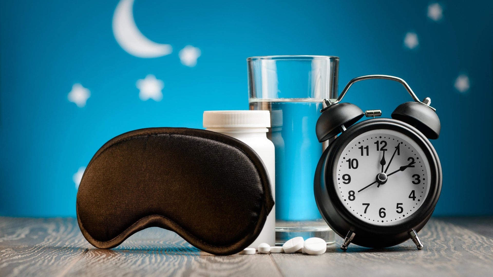 Sleep aid essentials with pills, eye mask, and clock.
