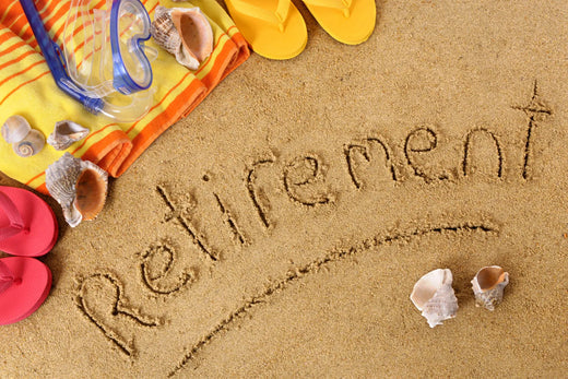 Retirement written in sand with beach gear and seashells.