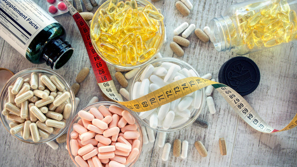 Various dietary supplements and pills with measuring tape.